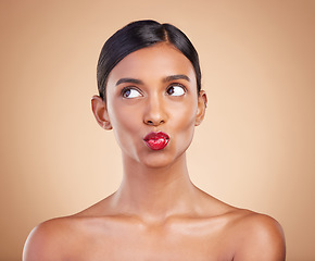 Image showing Red lipstick, beauty and makeup on a woman in studio for cosmetics, skin glow and shine product. Indian female model thinking and kiss on beige background for skincare, self care and lips with color