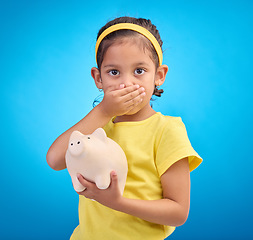 Image showing Piggy bank, shocked or surprised child in portrait isolated on blue background savings mistake or investment risk. Wow face of girl kid and saving jar or container for finance or money fear in studio