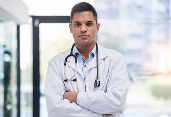 Image showing Portrait, man and doctor with arms crossed, focused and confident in hospital, clinic and surgery. Serious, proud and young medical worker in lab coat for healthcare services, wellness and commitment