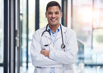 Image showing Portrait, man doctor and smile with arms crossed, confidence and professional medicine in hospital. Happy young healthcare worker in lab coat, medical services or expert commitment of pride in clinic