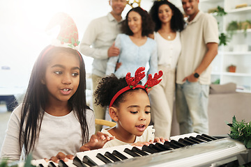 Image showing Children, singing and Christmas piano songs on a holiday or vacation excited in a home or house with a happy family. People, celebrate and kids make music or song together in celebration and bonding