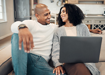 Image showing Happy, love and couple on a sofa with laptop in the living room of their modern house. Happiness, romantic and young man and woman in conversation while browsing on social media or internet together.