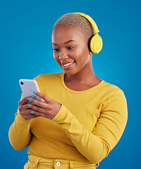 Image showing Happy, phone and music with black woman in studio for streaming, multimedia and browsing. Search, smile and audio with female and headphones on blue background for listening, online radio and songs