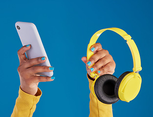 Image showing Closeup, hands and smartphone with headphones, streaming music and audio against blue studio background. Zoom, hand and technology with cellphone, headset or radio with sounds, internet or connection