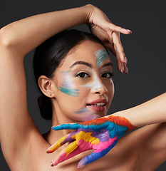 Image showing Woman, portrait and beauty with rainbow paint art on hand and face in studio with a smile. Creative skin and makeup on female aesthetic model on gray background for lgbtq color inspiration on hands