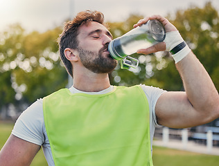 Image showing Drinking water, fitness and hydration with a sports man outdoor for a competitive game or event. Exercise, training and health with a male athlete taking a drink from a bottle during a break or rest