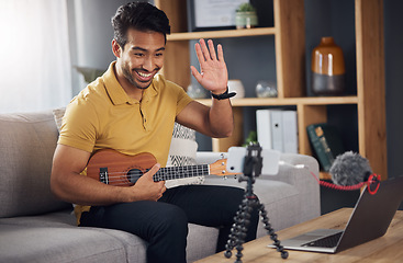 Image showing Podcast, guitar and laptop with a man online to wave and coach during live streaming lesson. Asian male person happy on home sofa with a ukulele as content creator teaching music on education blog