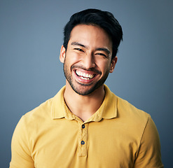 Image showing Portrait, happy and carefree with a man in studio on a blue background feeling confident or positive. Face, smile and cheerful with a handsome young male posing on a color wall looking relaxed