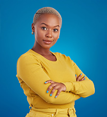 Image showing Portrait, fashion and arms crossed with a black woman on a blue background in studio feeling confident. Serious, focus or empowerment and an attractive young female looking proud with confidence