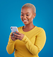 Image showing Phone, typing and black woman in studio with smile for social media, text message and browse website. Communication mockup, technology and girl on internet, network and chat online on blue background