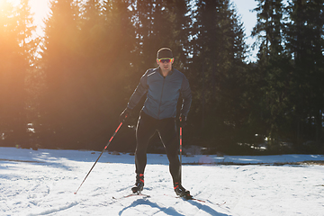 Image showing Nordic skiing or Cross-country skiing classic technique practiced by man in a beautiful panoramic trail at morning.