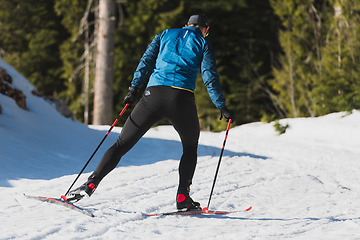 Image showing Nordic skiing or Cross-country skiing classic technique practiced by man in a beautiful panoramic trail at morning.
