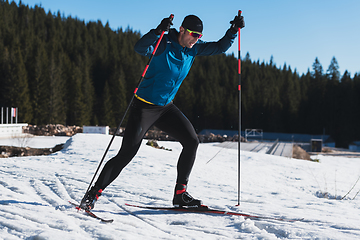 Image showing Nordic skiing or Cross-country skiing classic technique practiced by man in a beautiful panoramic trail at morning.