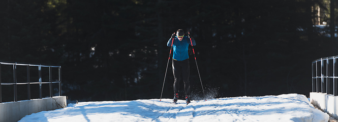 Image showing Nordic skiing or Cross-country skiing classic technique practiced by man in a beautiful panoramic trail at morning.