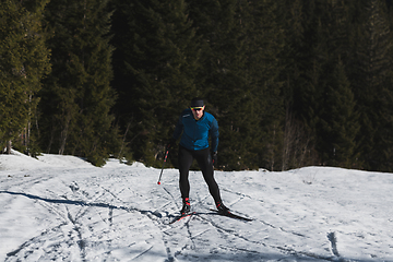 Image showing Nordic skiing or Cross-country skiing classic technique practiced by man in a beautiful panoramic trail at morning.