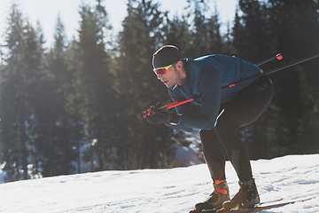 Image showing Nordic skiing or Cross-country skiing classic technique practiced by man in a beautiful panoramic trail at morning.