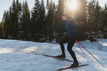 Image showing Nordic skiing or Cross-country skiing classic technique practiced by man in a beautiful panoramic trail at morning.