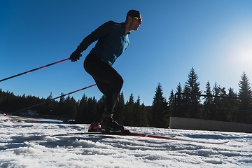 Image showing Nordic skiing or Cross-country skiing classic technique practiced by man in a beautiful panoramic trail at morning.