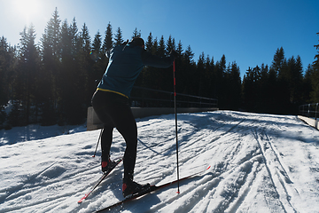 Image showing Nordic skiing or Cross-country skiing classic technique practiced by man in a beautiful panoramic trail at morning.