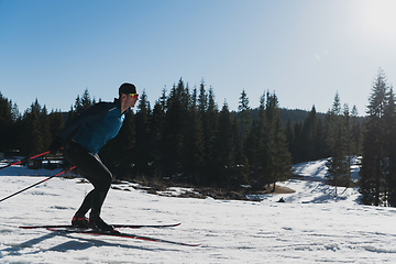 Image showing Nordic skiing or Cross-country skiing classic technique practiced by man in a beautiful panoramic trail at morning.