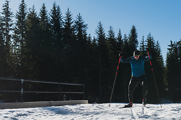 Image showing Nordic skiing or Cross-country skiing classic technique practiced by man in a beautiful panoramic trail at morning.