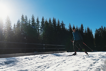Image showing Nordic skiing or Cross-country skiing classic technique practiced by man in a beautiful panoramic trail at morning.