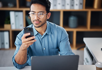 Image showing Phone, serious and businessman texting on mobile app in company office as internet or online communication. Laptop, cellphone and man employee startup entrepreneur networking or searching the web