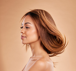 Image showing Beauty, hair and salon with a model black woman in studio on a beige background for keratin treatmet. Face, haircare or shampoo and an attractive young female posing with the wind in her hairstyle