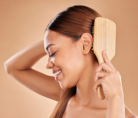 Image showing Woman, beauty and hair brush for healthy growth and shine or texture on a brown background. Smile of aesthetic female happy in studio brushing for natural keratin treatment haircare results profile