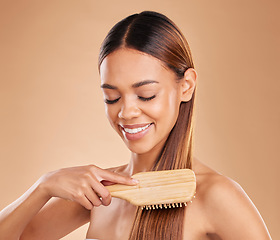 Image showing Woman, beauty and brushing hair for growth and shine for healthy texture on a brown background. Smile of aesthetic female happy in studio with a brush for natural keratin treatment haircare results