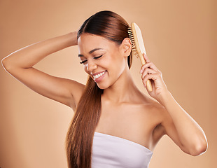 Image showing Smile, beauty and woman brushing hair for growth and shine for healthy texture on brown background. Aesthetic female model happy in studio with a brush for natural keratin treatment haircare results