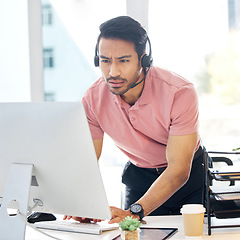 Image showing Serious asian man, call center and computer in customer service or problem solving at office desk. Confused male consultant or agent standing by PC in telemarketing research or browsing with headset