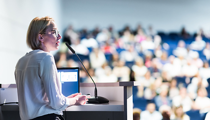 Image showing Female speaker giving a talk on corporate business conference. Unrecognizable people in audience at conference hall. Business and Entrepreneurship event.