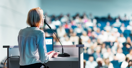 Image showing Female speaker giving a talk on corporate business conference. Unrecognizable people in audience at conference hall. Business and Entrepreneurship event.