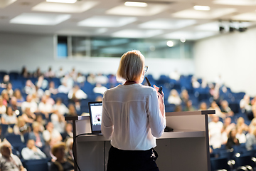 Image showing Female speaker giving a talk on corporate business conference. Unrecognizable people in audience at conference hall. Business and Entrepreneurship event.