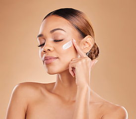Image showing Face, beauty skincare and woman with cream in studio isolated on a brown background. Dermatology, cosmetics and mixed race female model with lotion, creme or facial moisturizer product of skin health