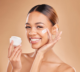 Image showing Skincare, face and woman with cream container in studio isolated on a brown background. Dermatology portrait, cosmetics or happy female model apply lotion, creme or moisturizer product of skin health