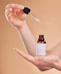 Image showing Hands, serum bottle and pipette for skincare in studio isolated on a brown background. Dermatology product, cosmetics and woman or model with hyaluronic acid, retinol or essential oil for anti aging.