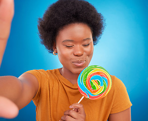 Image showing Woman, rainbow lollipop and selfie in studio with a smile and happiness or lgbtq pride on face. Black female model with a color candy on a blue background with sugar, sweets or dessert while excited