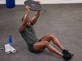 Image showing Black man holding weight plate for fitness, exercise and workout in gym. Strong bodybuilder weightlifting on floor for power, energy and heavy sports challenge in training, muscle gain and balance