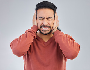 Image showing Asian man, frustrated and cover ears in studio for sound noise, mental health and headache by gray background. Young student guy, panic attack or anxiety with hands on head with anger, stress or fail