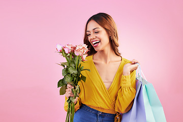 Image showing Happy, shopping bags and smile with woman and flowers in studio for retail, birthday and spring. Event, party and celebration with female and roses on pink background for sale, discount and romance