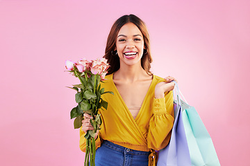 Image showing Happy, shopping bags and flowers with portrait of woman in studio for retail, birthday and spring. Event, party and smile with female and roses on pink background for sale, discount and romance