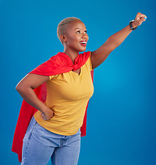 Image showing Black woman, superhero cape and flying in studio, blue background and pop culture fashion. Happy female model, cosplay character and superwoman costume of fist, courage or action of strong girl power