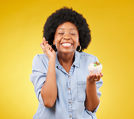 Image showing Birthday, wish and cupcake with a black woman on a yellow background in studio for celebration. Happy, smile and dessert with an attractive young female celebrating a special event on a color wall