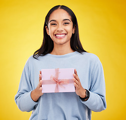 Image showing Happy woman, portrait and gift box in a studio with a smile from surprise present for birthday. Giveaway prize, isolated and yellow background of a young female student feeling positive and cheerful