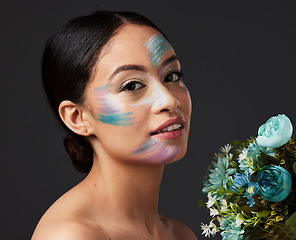 Image showing Beauty, woman and face paint with makeup, art with flowers and colorful aesthetic, color stroke in portrait on studio background. Skin, glow and cosmetics with creativity and female with smile