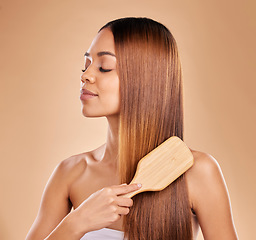 Image showing Brushing hair, beauty and woman with growth and shine for healthy texture on a brown background. Face of aesthetic female in studio with a brush for natural salon keratin treatment haircare results