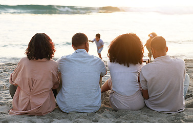 Image showing Family sitting on beach from the back, sunset and view of waves, zen and children playing in water together. Holiday, men and women relax in peace at evening ocean in Indonesia on tropical vacation.