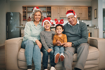 Image showing Portrait of grandparents with children in christmas hats relaxing on sofa in the living room. Happy, love and elderly couple sitting with kids with festive, holiday or xmas accessories at family home